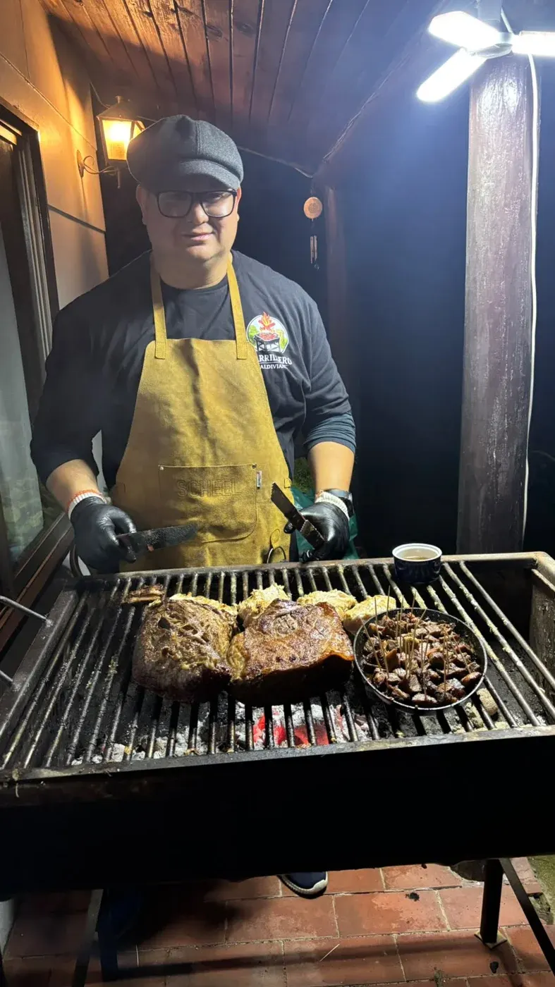 Gustavo, con delantal, atendiendo la parrilla de noche